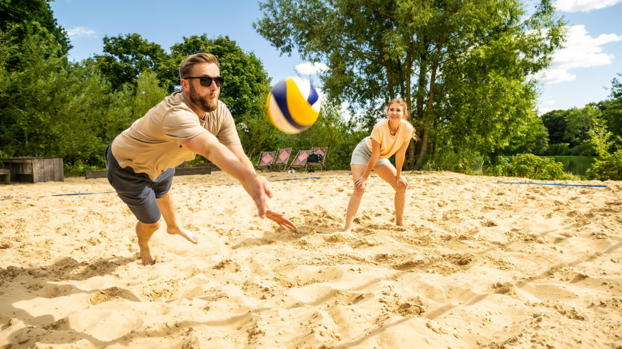 Zwei Personen spielen Beachvolleyball 